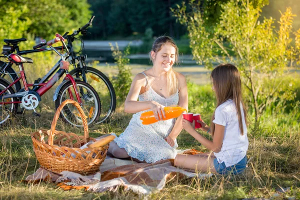 Madre joven haciendo un picnic junto al río con su hija. Madre po — Foto de Stock