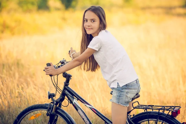 Tonas porträtt av vackra flicka poserar på cykel på ängen vid — Stockfoto