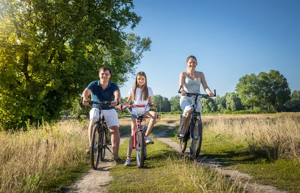Счастливая семья с дочкой проводят выходные на велосипедах — стоковое фото