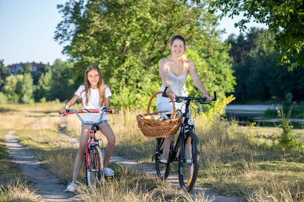 Молодая мама собирается на пикник с дочерью на велосипедах — стоковое фото