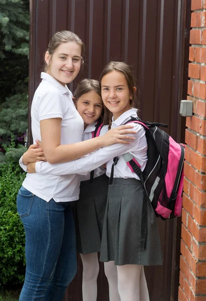 Feliz madre joven abrazando a sus hijas antes de ir a la escuela —  Fotos de Stock