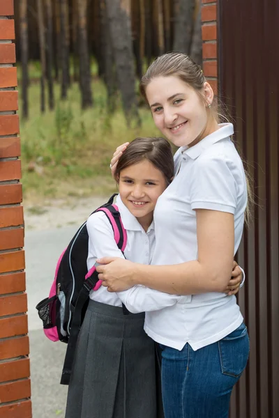 Junge Mutter umarmt ihre Tochter, bevor sie auf den Schoo geht — Stockfoto