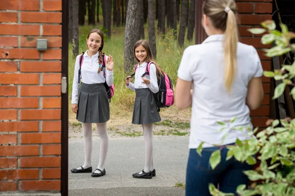 Mladá matka vidí své děti do školy a mával na ně — Stock fotografie