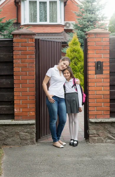 Lachende moeder haar dochter naar school voor te gaan knuffelen — Stockfoto