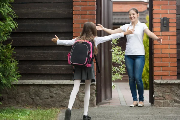 Glada mor möte dotter efter skolan framför huset — Stockfoto