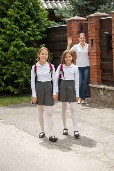 Madre joven saludando con la mano a sus hijas que van a la escuela —  Fotos de Stock