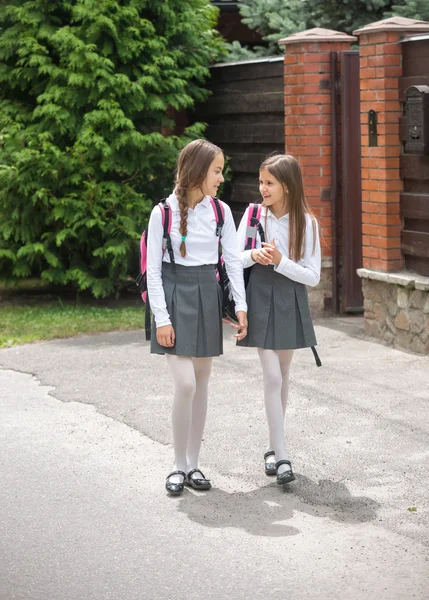 Meninas bonitas em uniforme andando para a escola e conversando — Fotografia de Stock