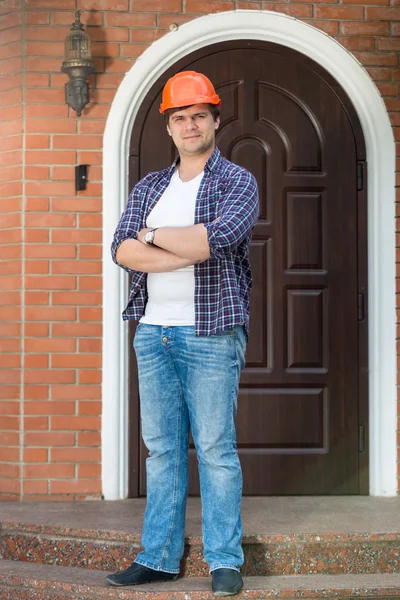 Joven contratista posando en una escalera frente a una casa nueva — Foto de Stock