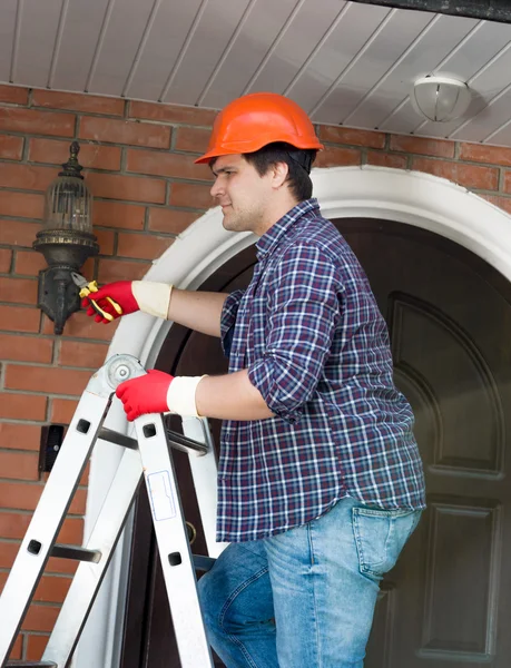 Elektricien bol in buiten lamp op huis muur wijzigen — Stockfoto