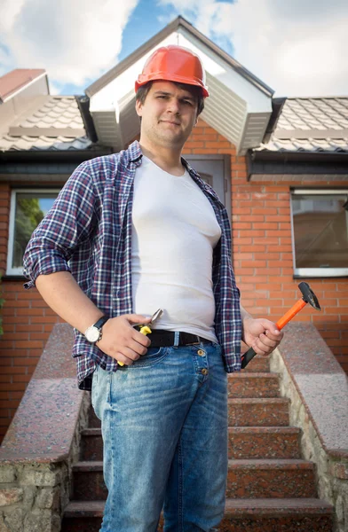 Улыбающийся строитель позирует перед готовым домом — стоковое фото