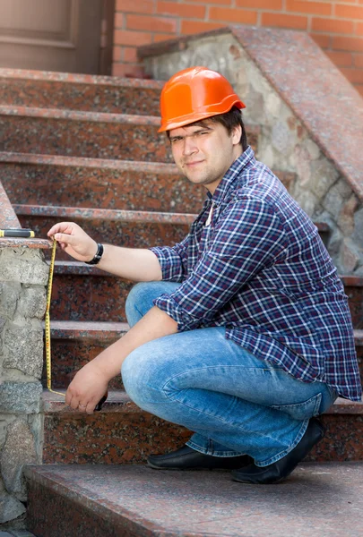 탭을 측정 하 여 돌 계단을 측정 하는 남성 노동자 미소 — 스톡 사진