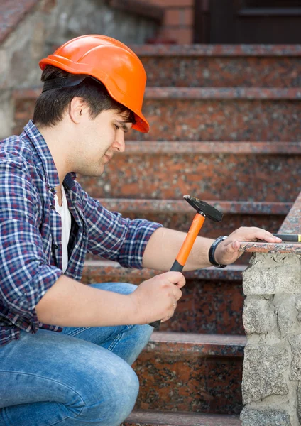 Joven trabajador en casco reparando vieja escalera de piedra — Foto de Stock