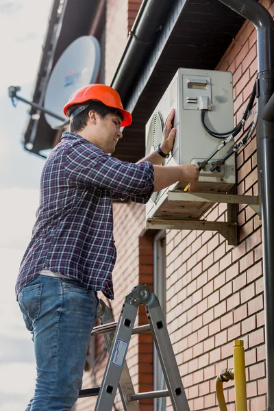 Elettricista in piedi su scaletta e riparazione condizionatori d'aria — Foto Stock