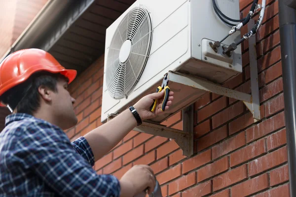 Tekniker i hardhat ansluta utomhus luftkonditionering enhet — Stockfoto