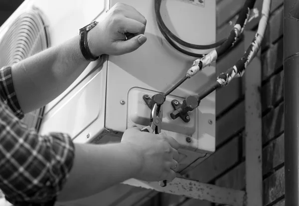 Black and white photo of electrician repairing air conditioning — Stock Photo, Image