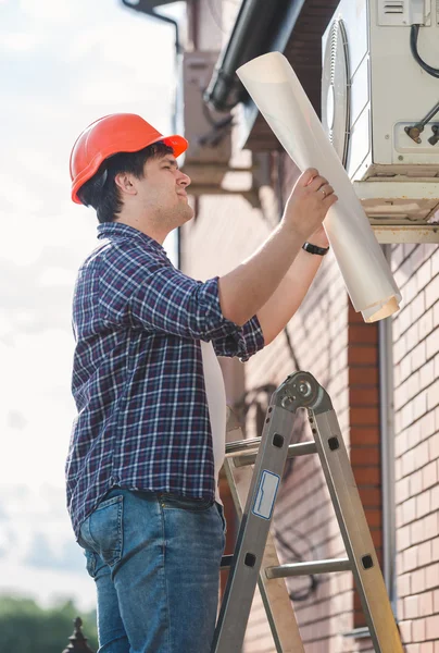 Ingeniero examinando el sistema de aire acondicionado y comparándolo con — Foto de Stock