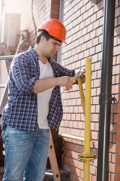 Mladý instalatér v bezpečnostní přilba opravy potrubí — Stock fotografie