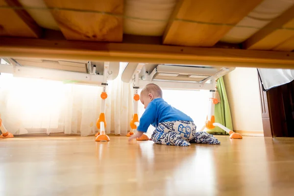 Roztomilý 9 měsíců starý chlapeček plazení pod postel — Stock fotografie
