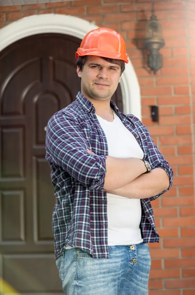 Lachende bouwvakker met handen gevouwen poseren tegen doo — Stockfoto