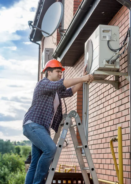 Jonge technicus reparatie buiten airconditioning unit — Stockfoto