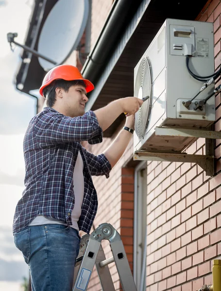 Mannelijke technicus buiten airconditioningsysteem herstellen — Stockfoto