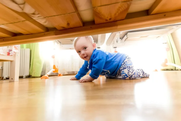 Chlapeček procházení na podlaze a při pohledu pod postelí — Stock fotografie