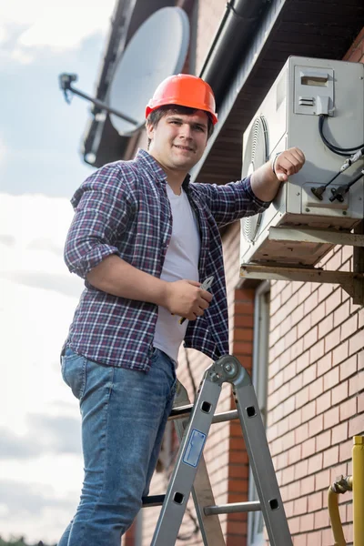 Jonge reparateur airconditioner te installeren op de buitenmuur — Stockfoto