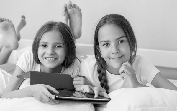 Black and white portrait of two teenage girls lying in bed with — Stock Photo, Image