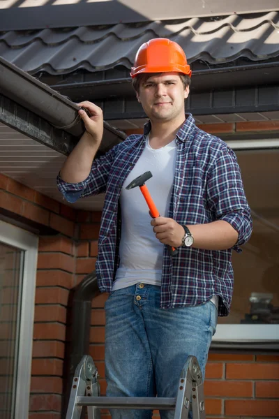 Sonriente trabajador de la construcción en escalera bajo el techo de la casa —  Fotos de Stock