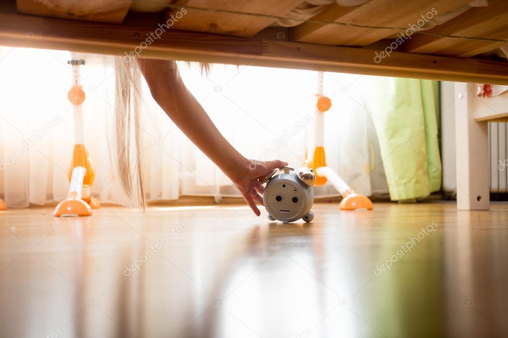 Young woman reaching under bed for alarm clock