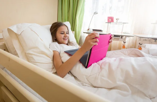 Porträtt av leende tonåring flicka med digital tablett vid säng — Stockfoto