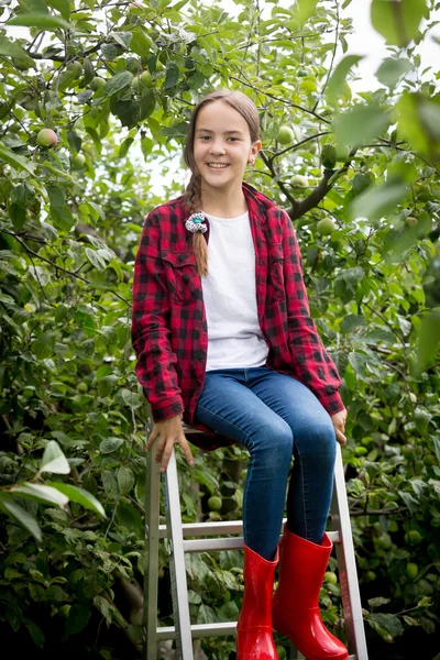 Young girl in red wellington boots  sitting on stepladder at gar — Stock Photo, Image