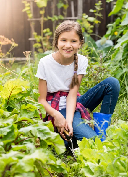 Chica sonriente que trabaja en el jardín y la excavación de lettu verde fresco — Foto de Stock