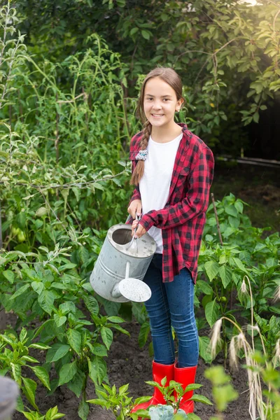 Giovane femmina giardiniere annaffiatoio letto giardino con verdure — Foto Stock