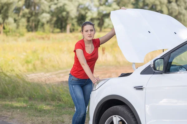 Retrato de la mujer molesta de pie en el coche roto en el borde de la carretera —  Fotos de Stock