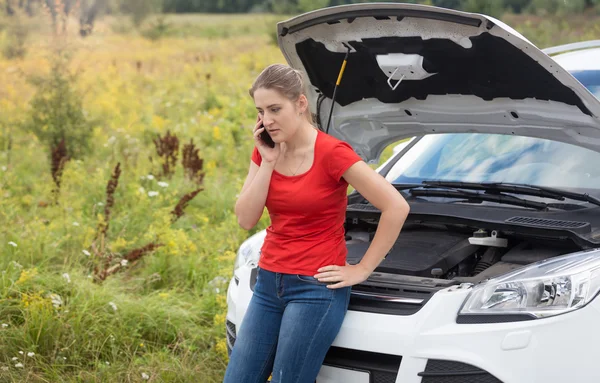 Ritratto di donna appoggiata a un'auto rotta con cappuccio aperto e talki — Foto Stock