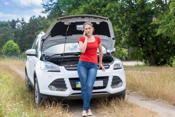 Mujer frustrada apoyándose en coche roto en el campo y pidiendo —  Fotos de Stock