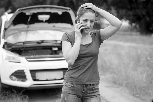 Zwart-wit beeld van triest vrouw stond op gebroken auto en ca — Stockfoto