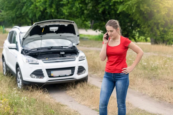 Vrouw permanent op gebroken auto op landelijke weg en cellph worden opgeroepen — Stockfoto