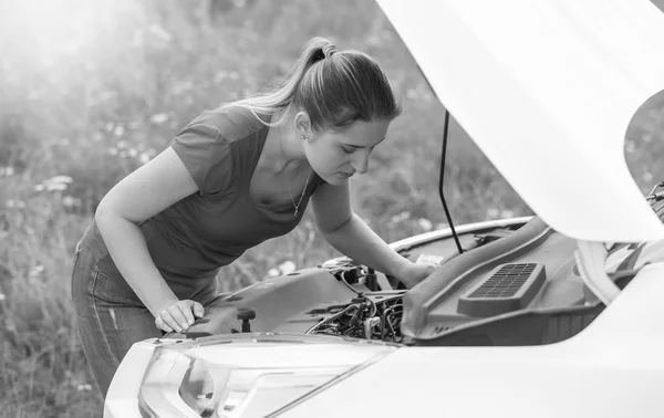 Черно-белый портрет женщины, смотрящей на двигатель сломанного — стоковое фото