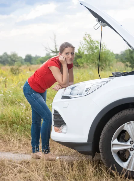 Mujer frustrada mirando el motor de coche roto en la carretera rural —  Fotos de Stock