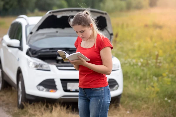 Retrato de la mujer estresada de pie en el coche roto y leyendo ow — Foto de Stock