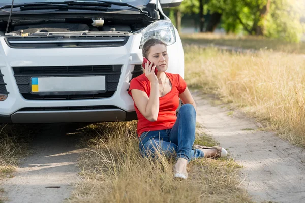 Portrait of woman sitting next to broken car and calling for ass — Stock Photo, Image