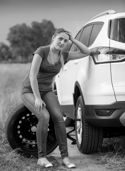 Preto e branco imagem de mulher triste sentado ao lado de carro quebrado em — Fotografia de Stock