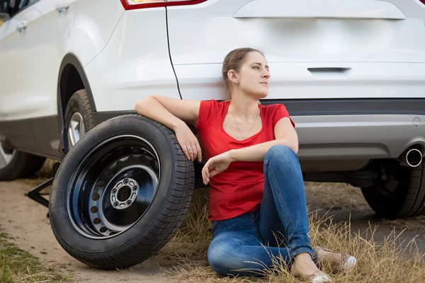 Upset woman sitting on ground at broken car — Stock Photo, Image