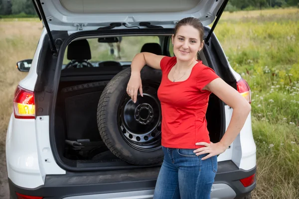 Portrait of beautiful woman taking out spare wheel to change on — Stock Photo, Image