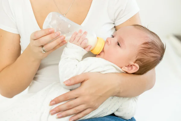 Madre dando leche de biberón a su bebé durmiendo en las manos — Foto de Stock