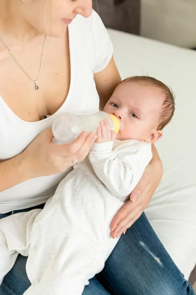 Nahaufnahme einer jungen Mutter, die ihren kleinen Jungen im Bett füttert — Stockfoto