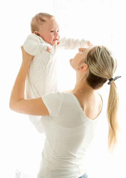 Feliz joven madre sosteniendo a su bebé de 3 meses en la ventana —  Fotos de Stock
