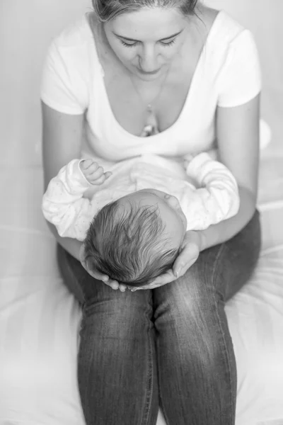 Schwarz-Weiß-Bild einer Mutter, die auf dem Bett sitzt und ihr Kind hält — Stockfoto